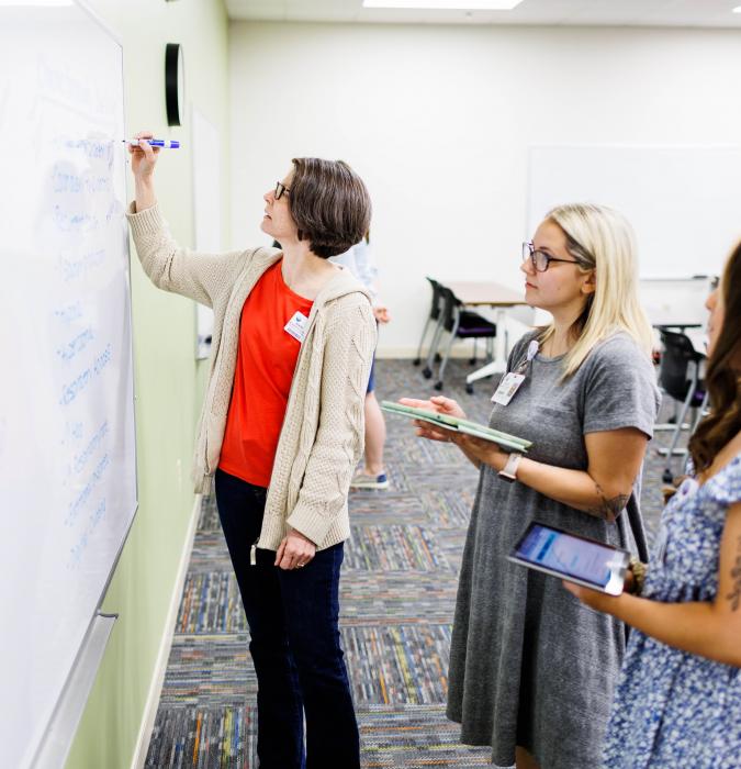A Centra College instructor teaches her class on a whiteboard. 